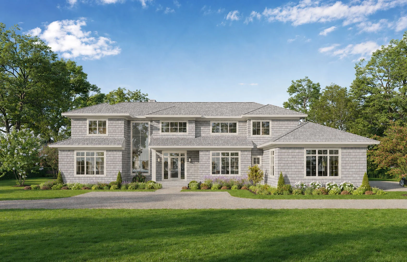 A large, two-story gray house with many windows and a well-kept lawn, surrounded by green trees and shrubs, under a blue sky with scattered clouds.